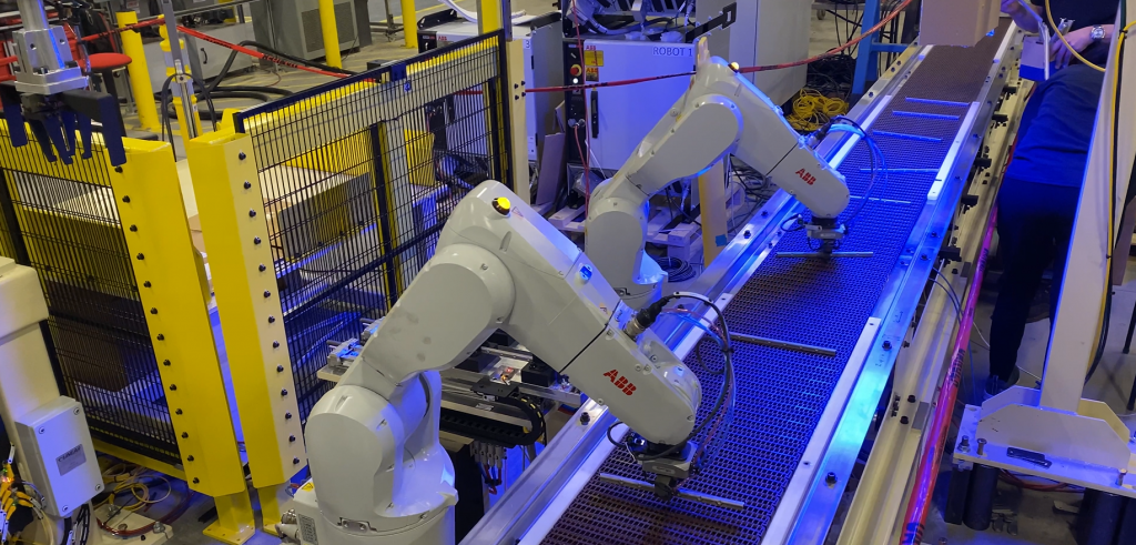 Two ABB robots picking up small parts on a conveyor belt using vision light technology.
