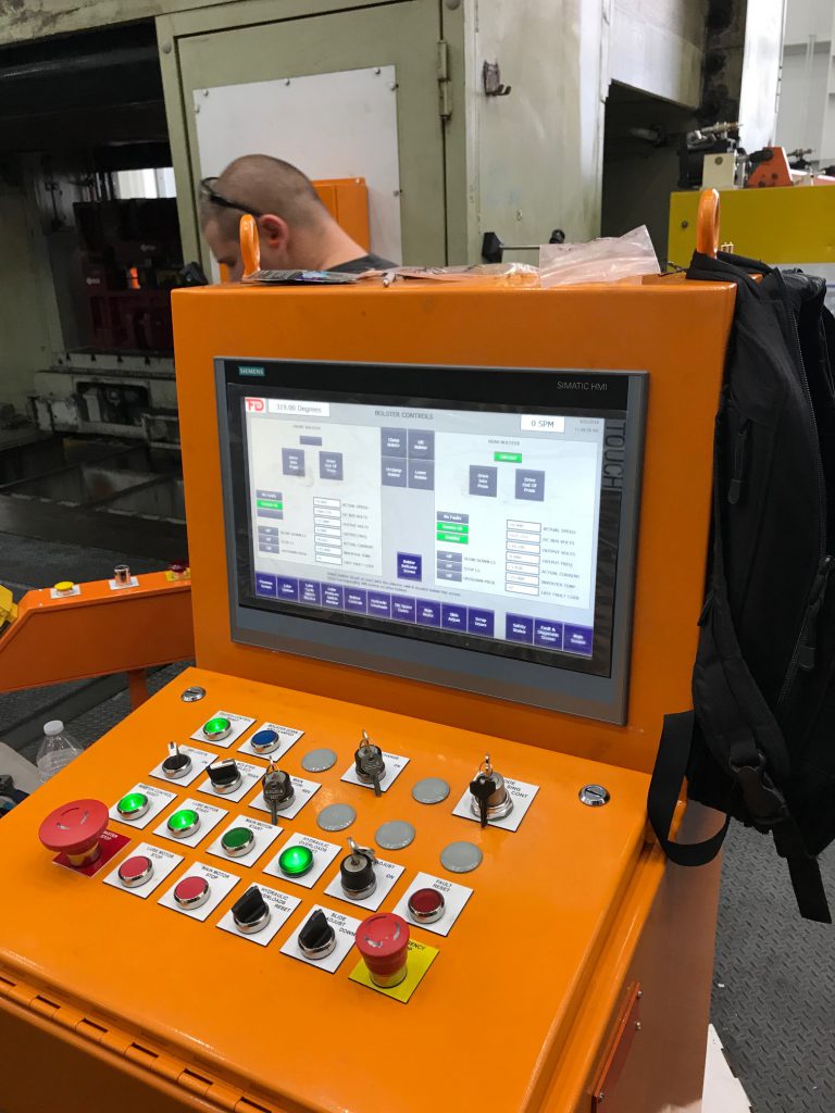 An image of an orange, Linear Automation press automation control module in a factory.